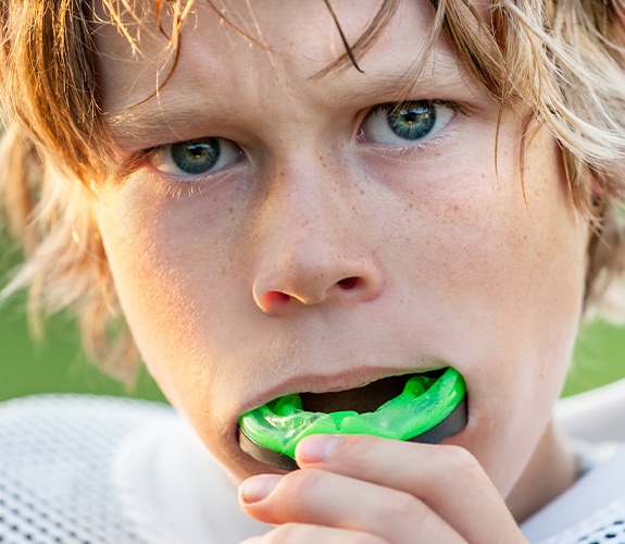 Young athlete placing athletic mouthguard