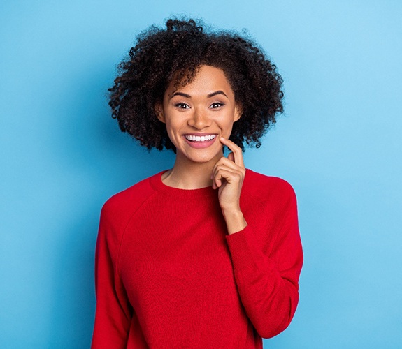 Woman in red sweater smiling after learning the cost of cosmetic dentistry in Sycamore