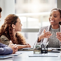 Woman seated at a table at work with her colleagues