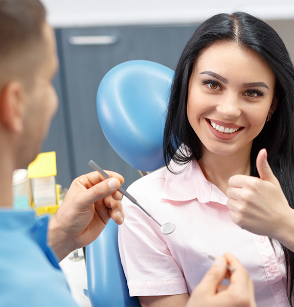 Woman in dental chair giving dentist a thumbs up