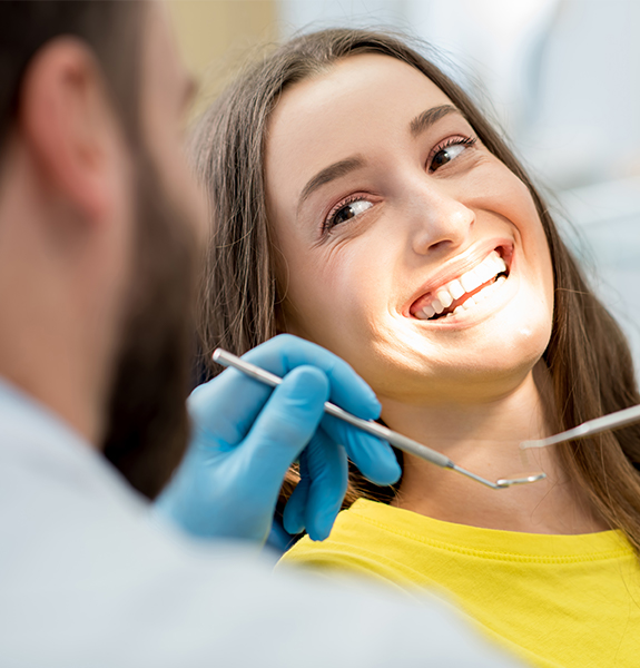 Woman in dental chair smiling at dentist