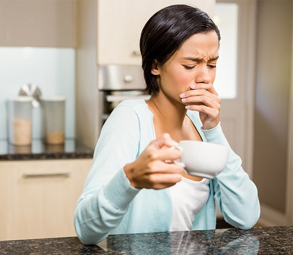 Woman in need of emergency dentistry covering her mouth