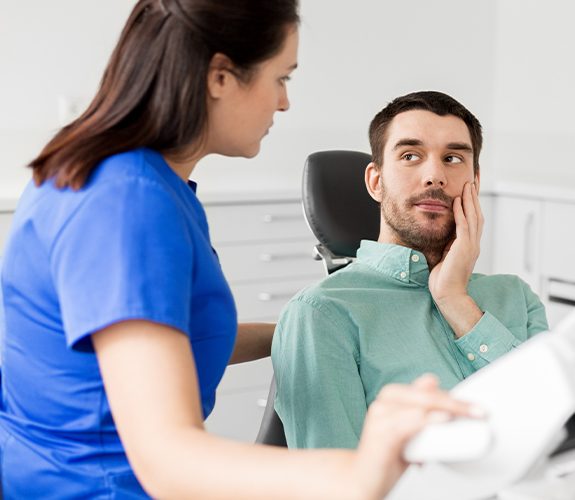 Man in need of emergency dentistry treatment holding his jaw