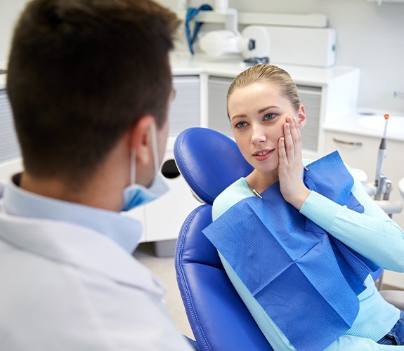 Woman in need of tooth extractions holding jaw in pain