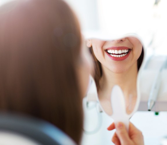 Woman looking at her smile in the mirror