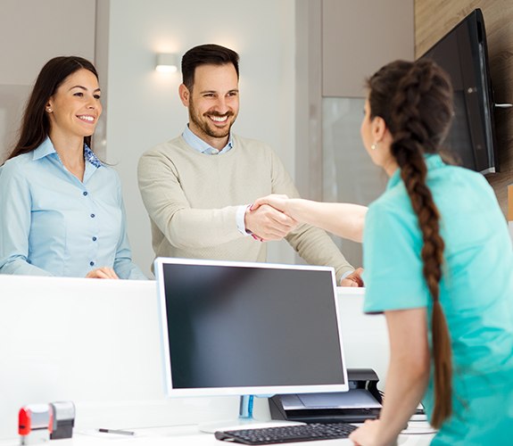 Man and woman checking in at dental office reception desk