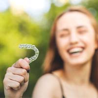 Female patient holding an aligner for Invisalign in Sycamore, IL