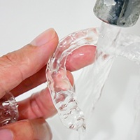 A person cleaning their Invisalign aligners with water