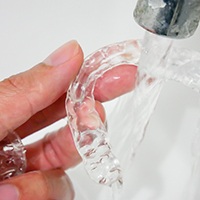 A person cleaning their aligners with water