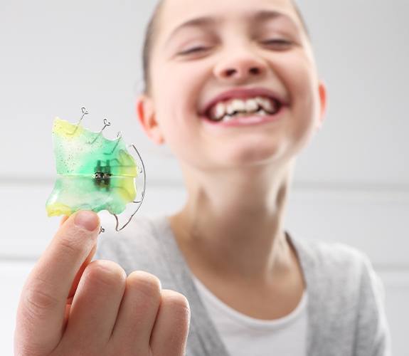Child holding an orthodontic appliance