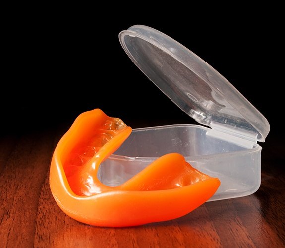 Young athlete placing athletic mouthguard