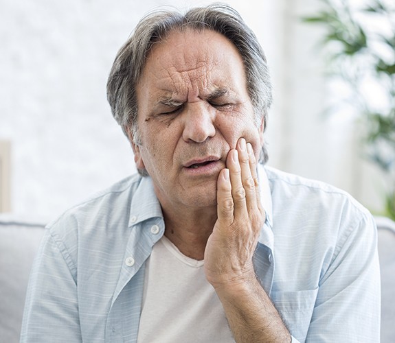 Man in need of T M J treatment holding jaw