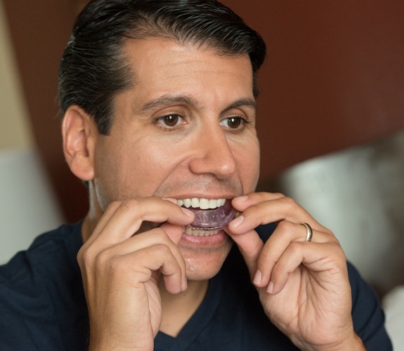 Man in need of sleep apnea therapy placing oral appliance