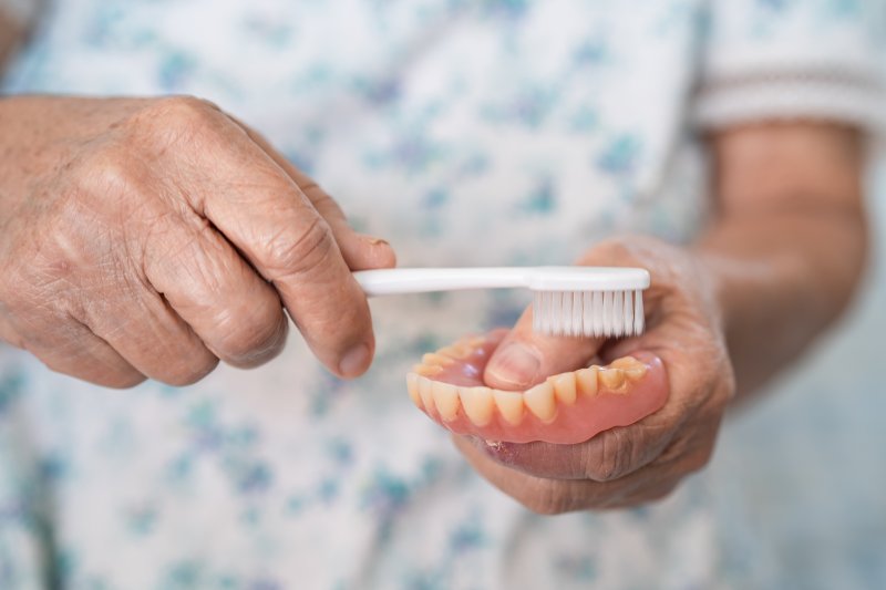 person brushing their dentures