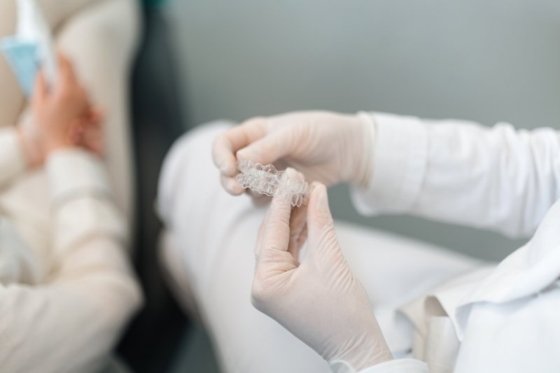 dentist holding clear aligners during an appointment