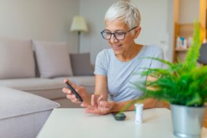 Older woman smiling while checking her blood sugar